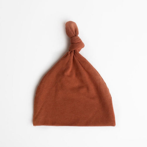 Top Knot Baby Hat in the colour Rust