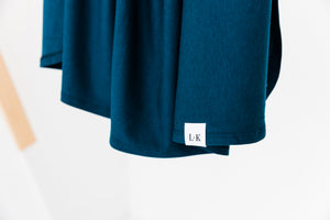 a close up of our branding tag on our Midnight Teal stretch swaddle blanket