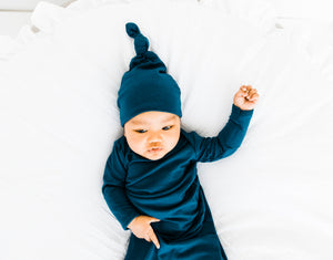 A baby boy wearing our Midnight Teal blue Top Knot hat and Knotted Gown both in sizes 0-3 months
