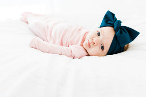 baby girl wearing our knotted gown in light pink and headband in midnight teal