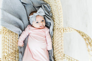 baby girl wearing heathered grey headband and pink knotted baby gown